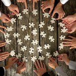 Businessmen Hands Holding Puzzle Pieces on Table