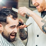 Hairdresser makes hairstyle a man with a beard